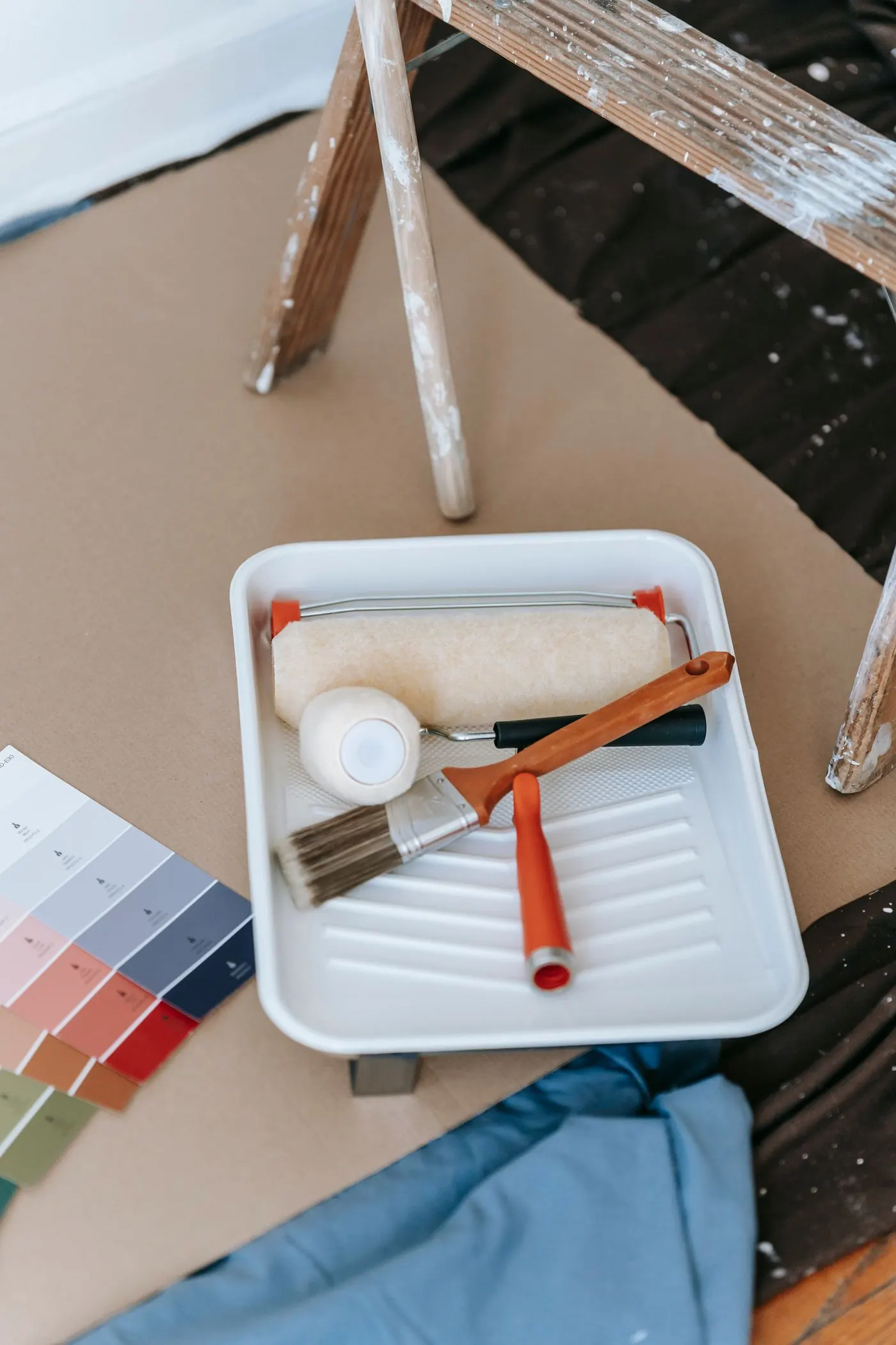 Roller, brushes and colour swatches on a paint tray