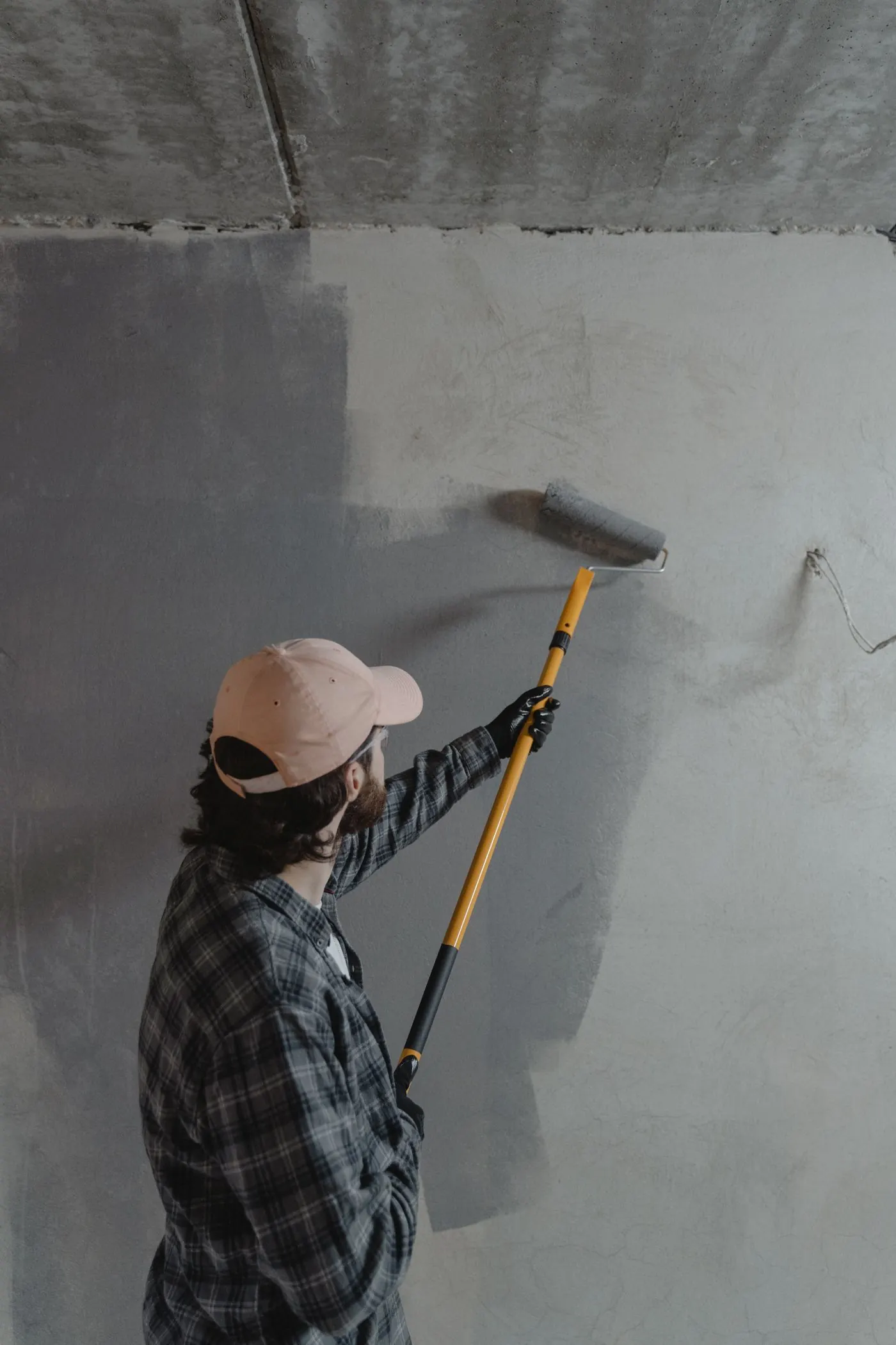 Painter rolling a wall with an extension pole