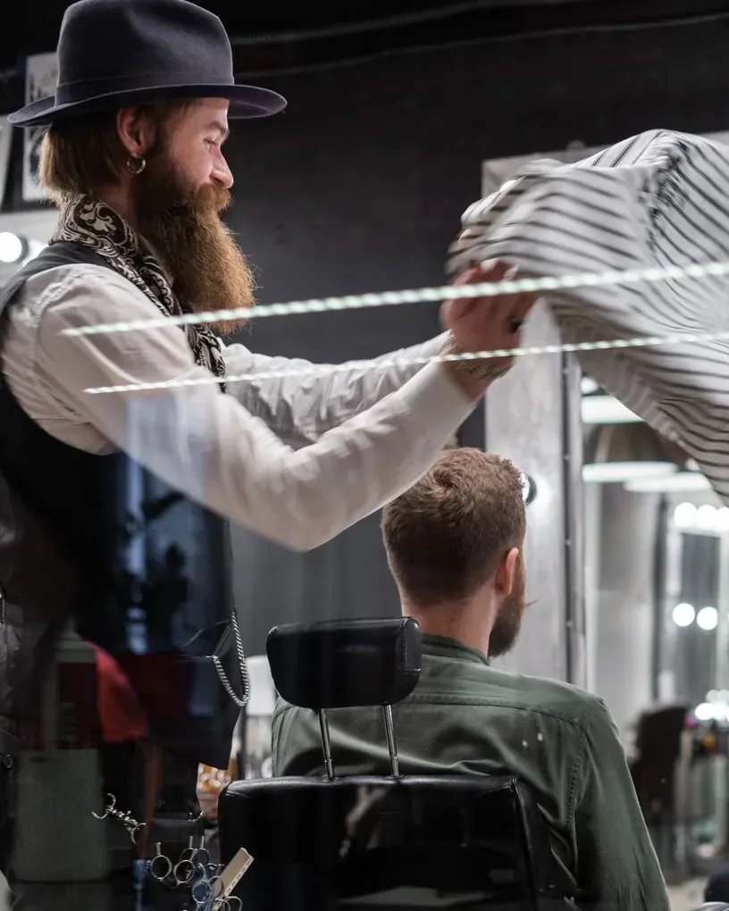 Barber putting a cape over a client at the chair
