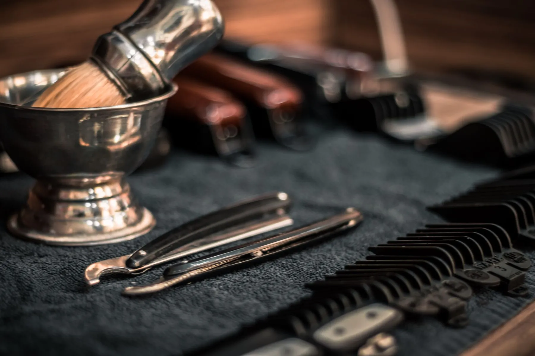 A shaving brush, bowl and straight razor on dark cloth