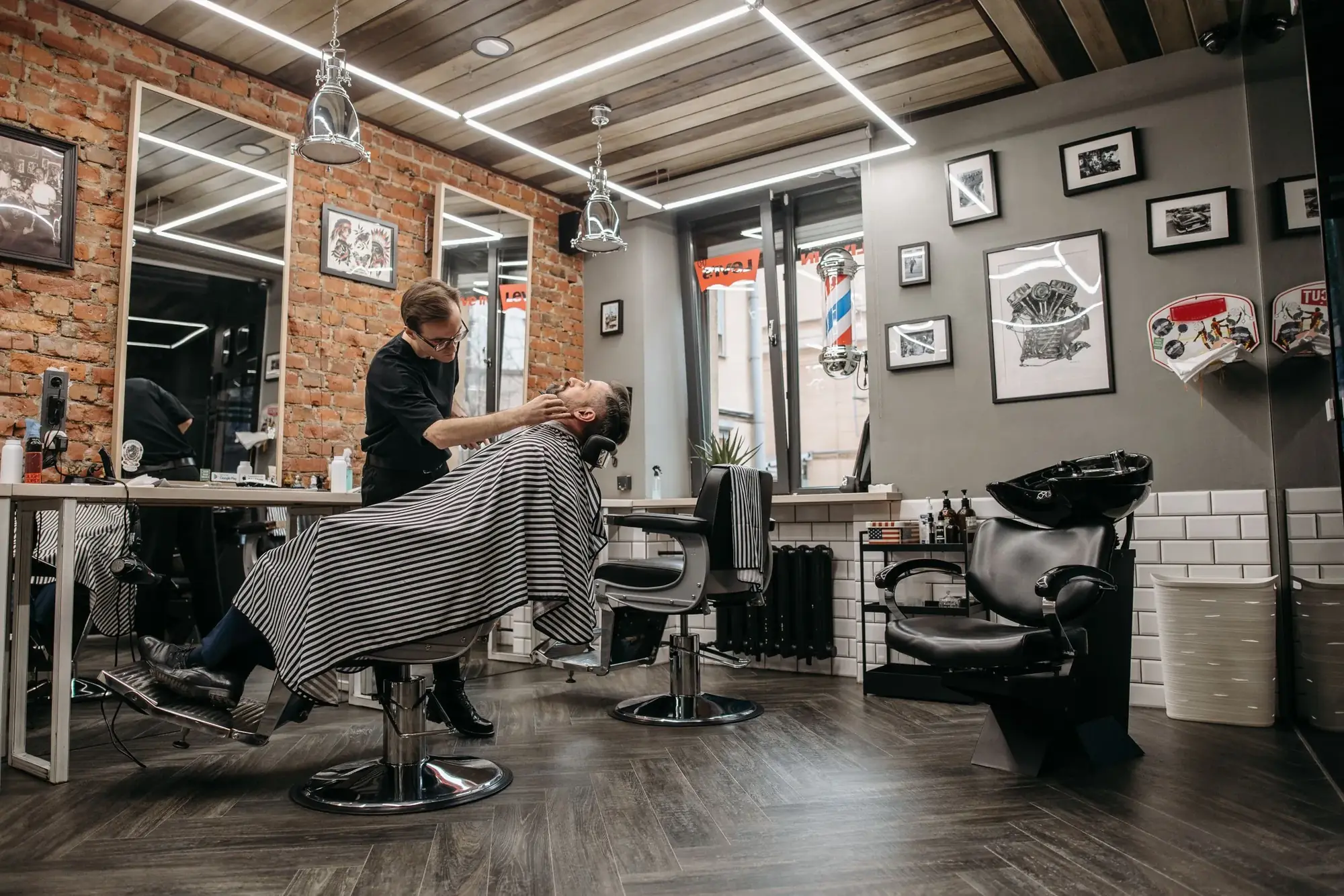A barber finishing a client's haircut in a brick walled Brunswick shop